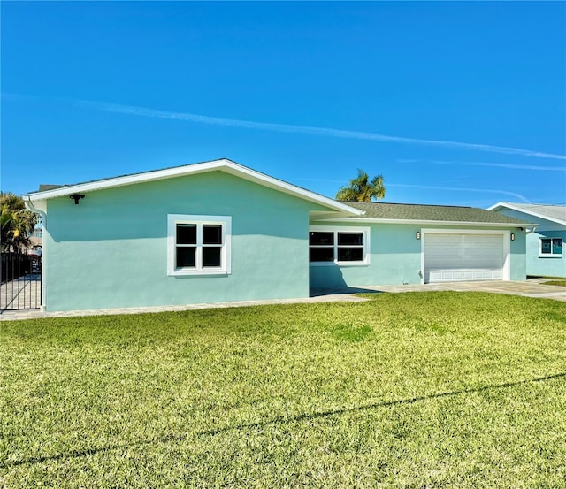 rear view of property with a lawn, fence, an attached garage, and stucco siding