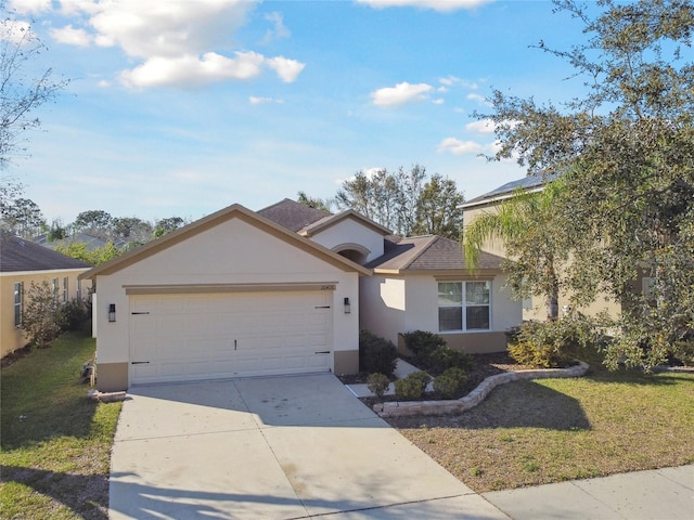 ranch-style home with concrete driveway, stucco siding, roof with shingles, an attached garage, and a front yard