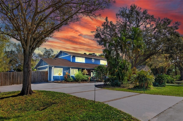 traditional-style house with concrete driveway, a front yard, and fence