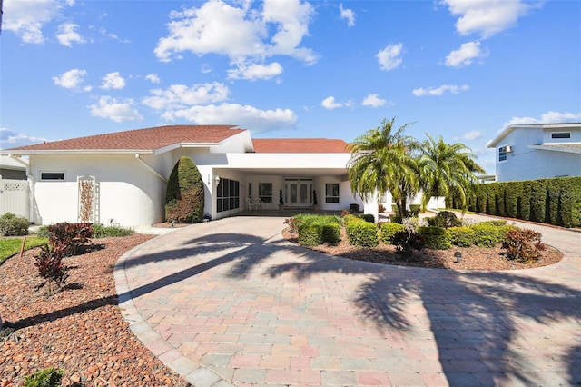 mediterranean / spanish house with an attached carport, decorative driveway, and stucco siding