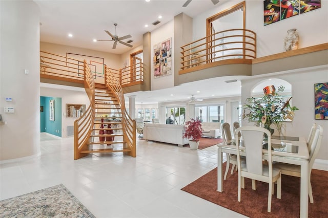 dining space with stairs, ceiling fan, a high ceiling, and recessed lighting