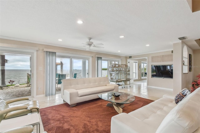 living area with ornamental molding, light tile patterned flooring, visible vents, and a textured ceiling