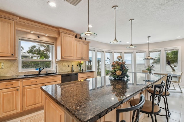 kitchen featuring tasteful backsplash, black dishwasher, a breakfast bar, and a sink