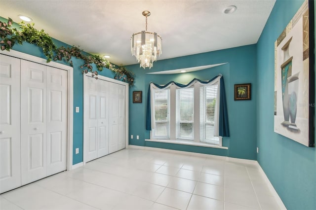 interior space with a chandelier, tile patterned floors, and baseboards