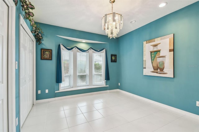 empty room with a chandelier, baseboards, and tile patterned floors