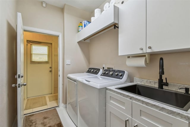 washroom with cabinet space, a sink, washing machine and clothes dryer, and light tile patterned floors