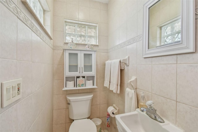 bathroom featuring a sink, tile walls, and toilet