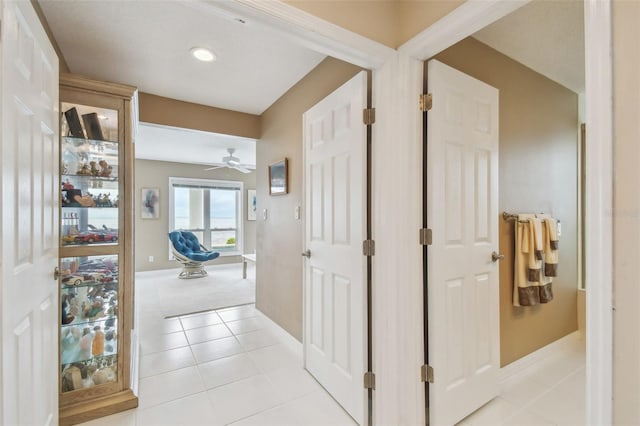 hall featuring baseboards and light tile patterned floors