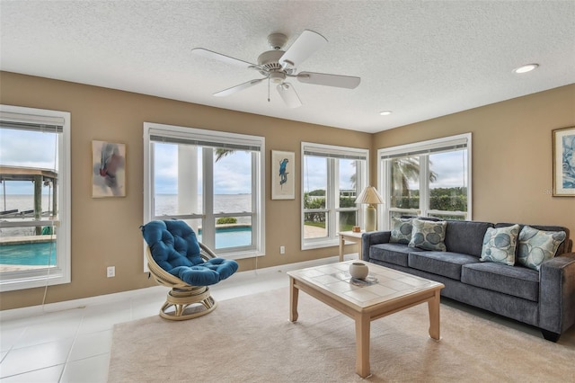 living room with a textured ceiling, ceiling fan, light tile patterned flooring, recessed lighting, and baseboards