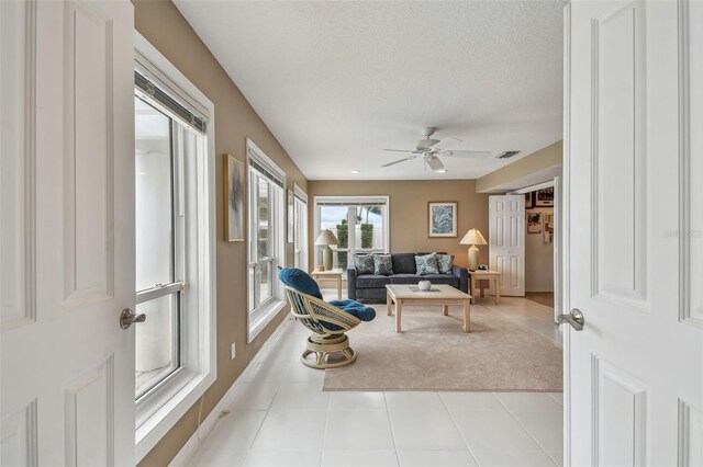 interior space featuring a ceiling fan, visible vents, a textured ceiling, and tile patterned floors