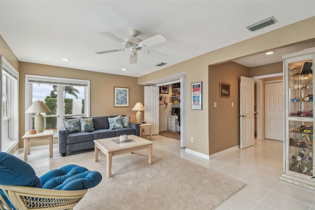 living room with light tile patterned floors, a textured ceiling, visible vents, and baseboards