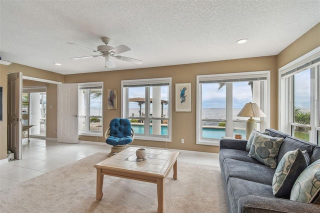 living room featuring light colored carpet, plenty of natural light, a textured ceiling, and light tile patterned floors