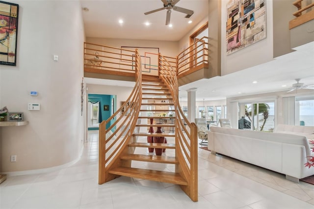 stairs featuring baseboards, a towering ceiling, ceiling fan, tile patterned flooring, and recessed lighting