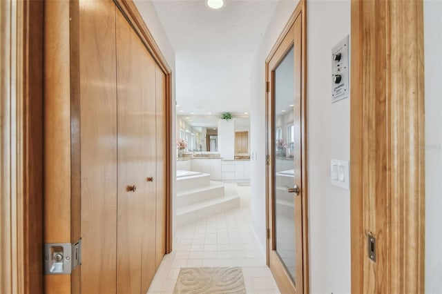 hall featuring a textured ceiling, light tile patterned flooring, and recessed lighting