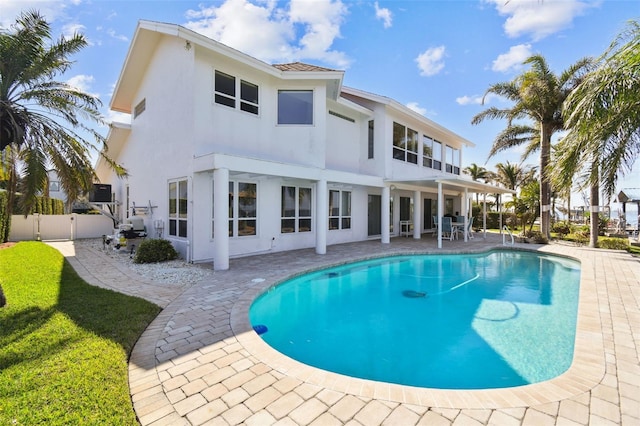 rear view of house featuring a fenced in pool, stucco siding, a gate, a patio area, and fence