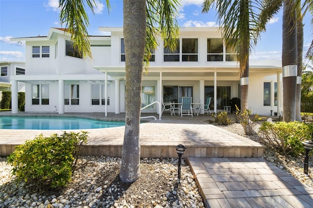 back of house featuring an outdoor pool, a patio area, and stucco siding