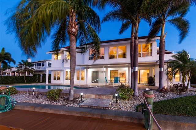 rear view of house with a fenced in pool, a patio, and stucco siding