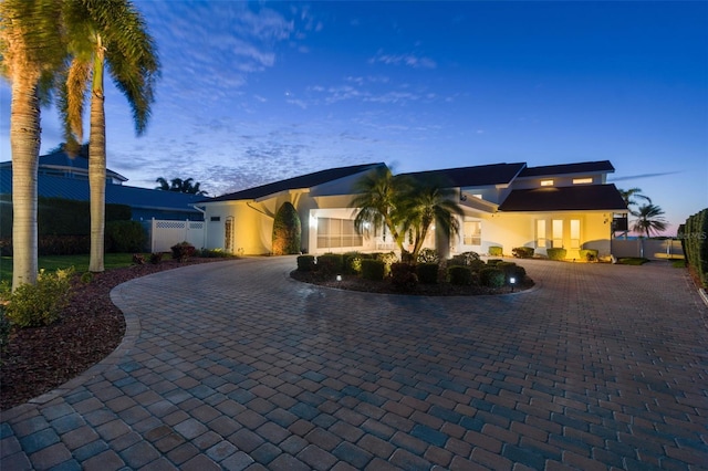 view of front of property featuring fence, curved driveway, and stucco siding