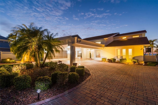 back of house featuring decorative driveway and stucco siding