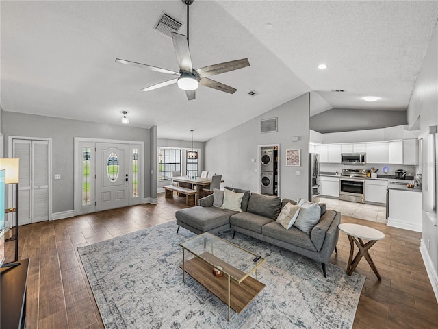 living room with visible vents, stacked washing maching and dryer, and wood finished floors