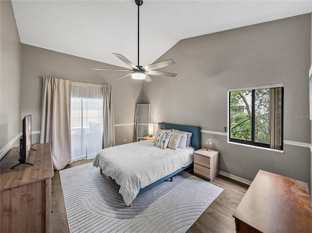 bedroom featuring lofted ceiling, a textured ceiling, wood finished floors, a ceiling fan, and baseboards