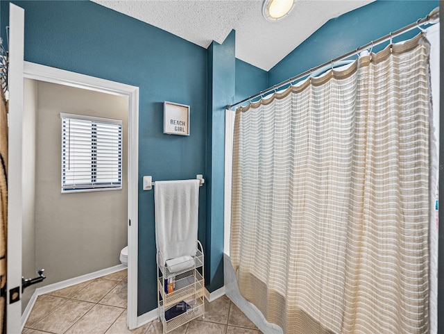 full bathroom featuring baseboards, toilet, tile patterned flooring, vaulted ceiling, and a textured ceiling