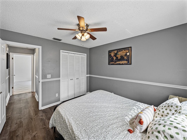 bedroom featuring baseboards, visible vents, wood finished floors, a textured ceiling, and a closet