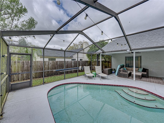 view of swimming pool featuring glass enclosure, fence, an outdoor hangout area, and a patio