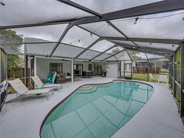 view of swimming pool featuring a patio, fence, a ceiling fan, and a lanai