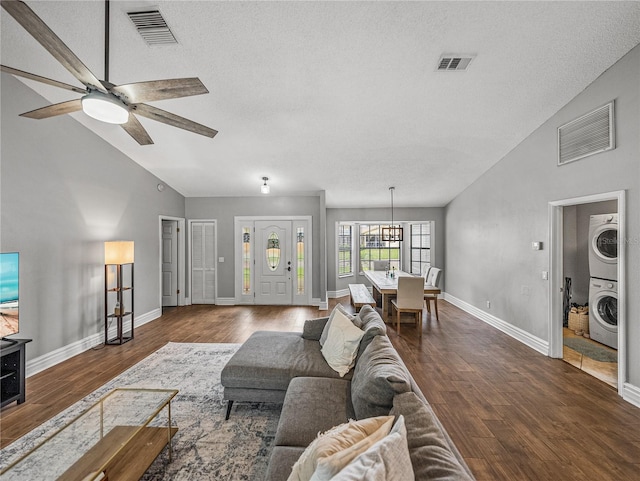 living room featuring a ceiling fan, visible vents, stacked washer / dryer, and wood finished floors