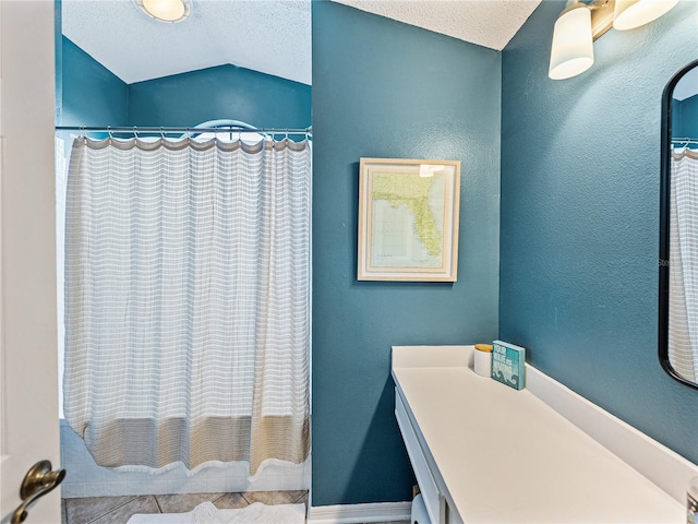 full bath with a textured wall, curtained shower, vaulted ceiling, and a textured ceiling