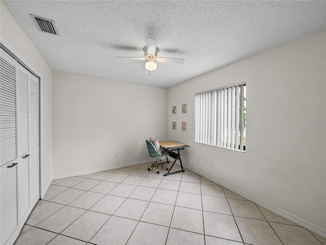 interior space with a textured ceiling, ceiling fan, visible vents, baseboards, and a closet