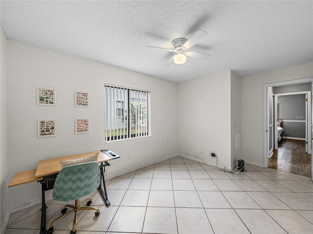 unfurnished office featuring ceiling fan, a textured ceiling, baseboards, and light tile patterned floors