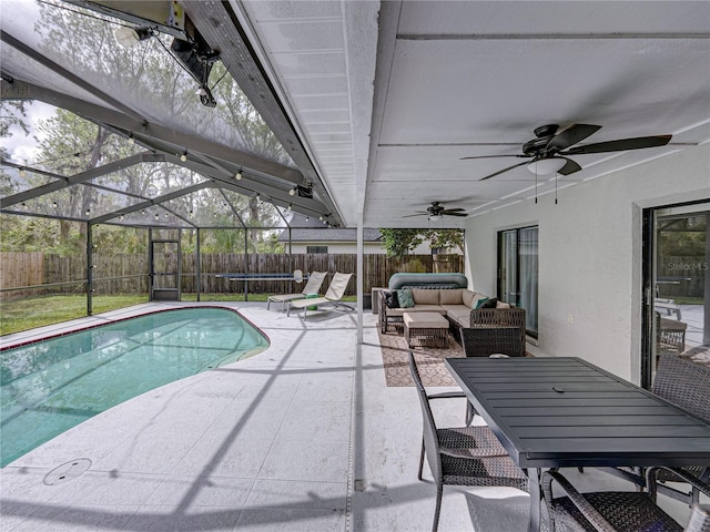 view of swimming pool with a patio, glass enclosure, a fenced backyard, outdoor lounge area, and a ceiling fan