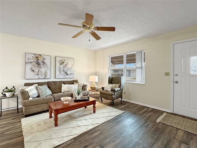 living room featuring a ceiling fan, dark wood-style flooring, a textured ceiling, and baseboards