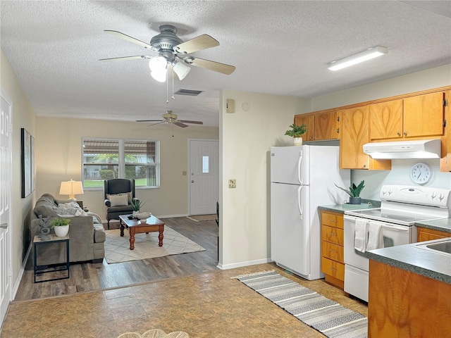 kitchen featuring white appliances, visible vents, brown cabinetry, dark countertops, and under cabinet range hood