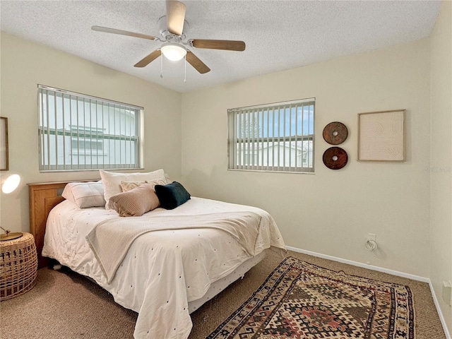 carpeted bedroom with ceiling fan, baseboards, and a textured ceiling