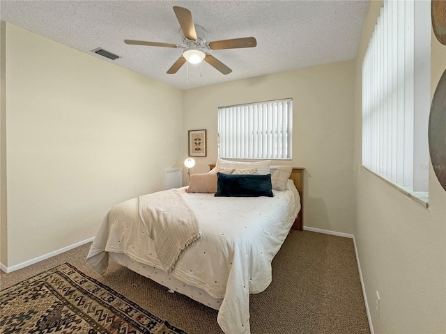 carpeted bedroom featuring a ceiling fan, visible vents, a textured ceiling, and baseboards