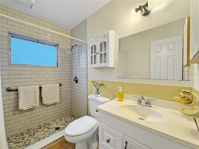 bathroom with a stall shower, vanity, toilet, and tile walls