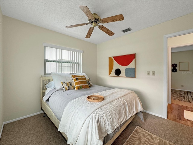 carpeted bedroom with a ceiling fan, baseboards, visible vents, and a textured ceiling