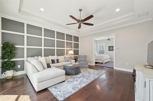 living room with recessed lighting, dark wood-type flooring, baseboards, a tray ceiling, and crown molding