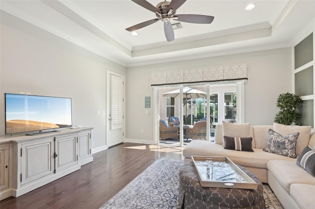 living area featuring baseboards, a ceiling fan, ornamental molding, dark wood-style flooring, and a tray ceiling