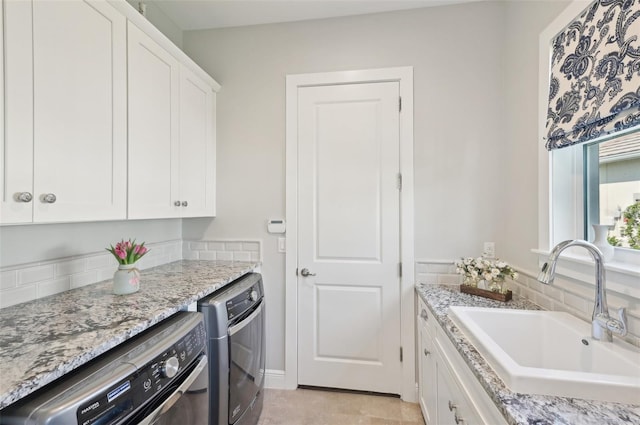 kitchen featuring light stone counters, white cabinetry, a sink, and dishwashing machine