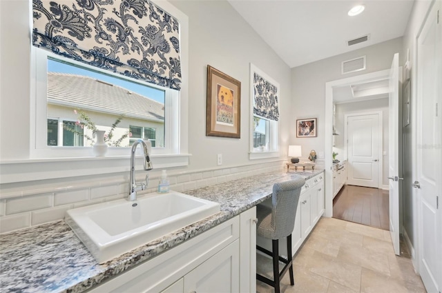 kitchen featuring built in study area, a sink, visible vents, and white cabinets