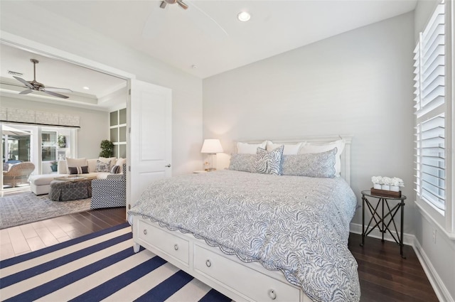 bedroom featuring recessed lighting, a tray ceiling, baseboards, and wood finished floors