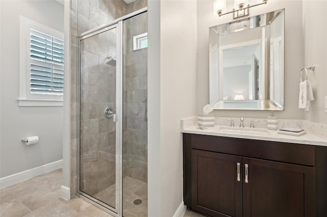 bathroom featuring a stall shower, vanity, and baseboards