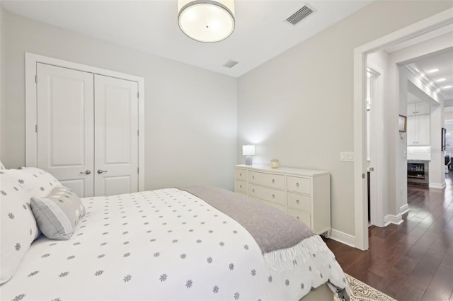 bedroom featuring dark wood-style floors, baseboards, visible vents, and a closet