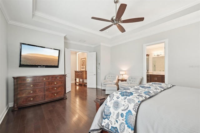 bedroom featuring dark wood-style floors, a tray ceiling, crown molding, ensuite bathroom, and baseboards