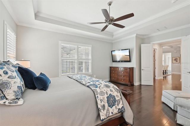 bedroom featuring a tray ceiling, crown molding, baseboards, and wood finished floors