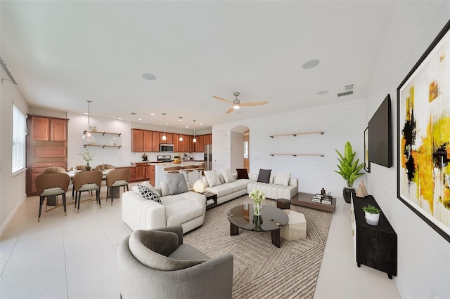 living area featuring light tile patterned floors, visible vents, arched walkways, a ceiling fan, and recessed lighting